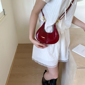 Sac demi-lune en cuir verni bordeaux élégant avec bandoulière et finition brillante