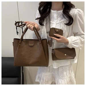 Detail view of brown crocodile texture tote bag with broad woven shoulder strap