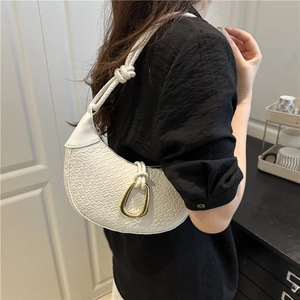 White woven crescent shoulder bag with gold buckle and knotted strap on female model
