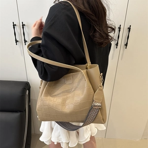 Beige crocodile pattern tote bag with herringbone strap on a stylish model in a suit