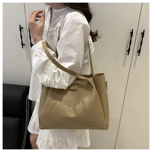 Detail of elegant khaki tote bag with crocodile pattern texture on a model shoulder