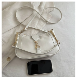 Close-up of white crescent shoulder bag with gold hardware and size reference phone