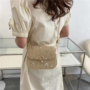Détail du sac selle en paille tressée avec broderie florale et fermoir doré