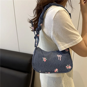 Blue denim underarm bag with pink bow floral print and pleated strap on model