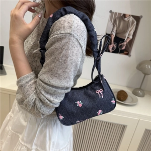 Blue denim underarm bag with pink rose embroidery and decorative bow accents