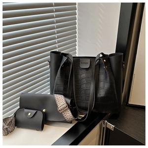 Three-piece set of black faux leather tote bags with stone pattern and woven strap detail