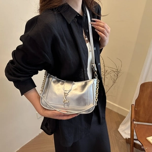 Chic silver crescent crossbody bag with chain strap worn by model over a black shirt