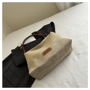 Detail of woven straw tote bag with brown leather label and stylish braided shoulder strap