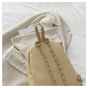 Detail of a chic cream PU leather backpack with silver chain strap and top handle design
