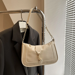 Close-up of cream PU leather underarm bag with gold chain strap on a hanger