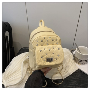 Detail of light yellow quilted mini backpack featuring metal studs and chain strap