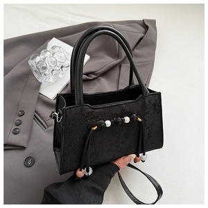 Close-up of black lace jacquard texture on handbag with pearl and knot detailing