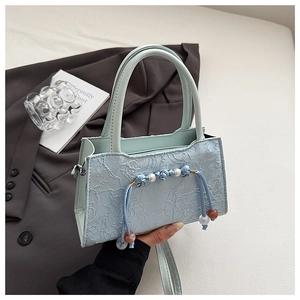 Detail of light blue lace handbag with pearl embroidery and elegant beaded tassels