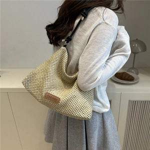 Minimalist woven straw shoulder bag with black knot straps and leather fashion label