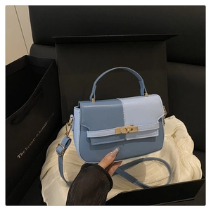 Detail view of contrast blue panelled handbag inside a premium gift box with pearls