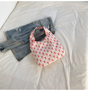Détail du sac fourre-tout crème avec motifs de nœuds rouges sur texture de tissu doux