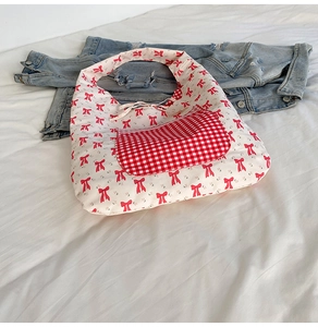 Détail du sac fourre-tout en toile à motifs de nœuds rouges avec poche à carreaux