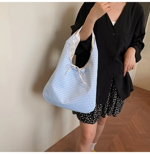 Détail du sac cabas à carreaux bleus avec nœud papillon et texture en toile légère