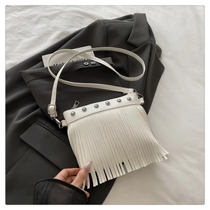 Top view of white leather fringe tote with silver rivets on a charcoal blazer
