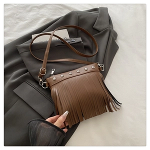 Detailed shot of brown bohemian tote bag featuring stylish fringe and metal rivet accents