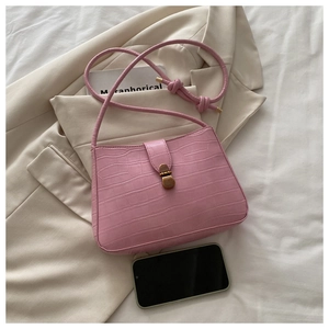 Détail du sac sous l'aisselle rose gaufré croco avec fermoir doré et téléphone témoin