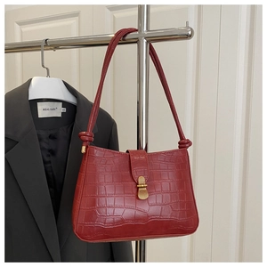 Détail du sac en cuir crocodile rouge foncé avec une boucle en métal doré élégante