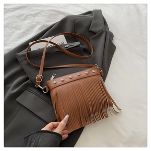 Detail of brown faux leather crossbody bag with silver studs and long fringe tassels