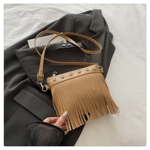 Detailed close-up of khaki tassel shoulder bag with silver rivets on soft fabric