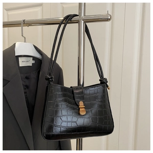 Détail du sac à bandoulière en crocodile noir avec fermoir doré et bandoulière nouée