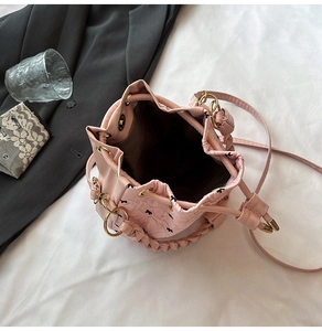 Vista dettagliata della borsa a secchiello rosa con fiocchi neri e fibbie dorate