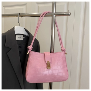 Gros plan du sac porté épaule rose à texture crocodile avec détails dorés vintage