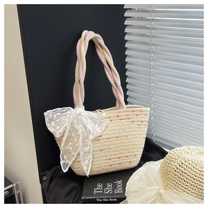 Detailed close-up of handmade woven straw bag with floral lace bow and pearl accent
