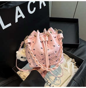 Dettaglio della borsa a secchiello rosa con fiocchi neri e ciondolo a pompon