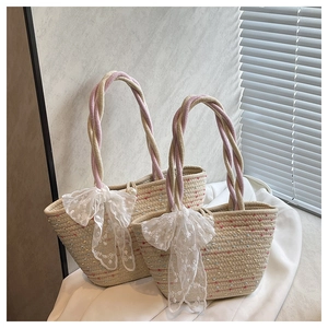 Detail of woven straw handbag featuring lace bow, pearl clasp and floral embroidery