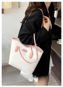 Detailed close-up of a white leather tote bag with pink straps and floral embossed texture