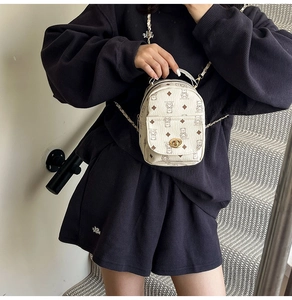Detail of cream mini backpack with brown bear prints and golden metallic twist lock closure