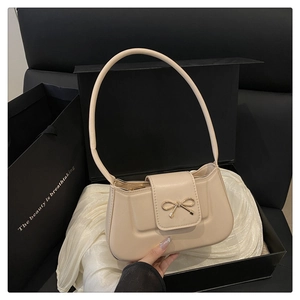 Vue détaillée du sac baguette beige avec boucle papillon et emballage cadeau de luxe