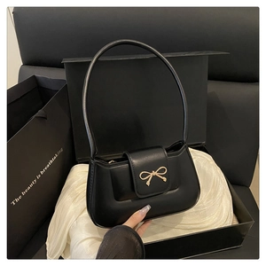 Détail d'un sac baguette noir mat doté d'un fermoir en métal doré en forme de nœud