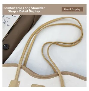Close-up of white embossed tote bag with slim brown shoulder straps and leather detail
