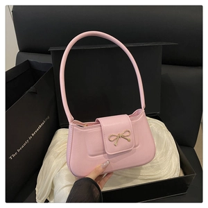 Détail du sac baguette rose avec boucle nœud dorée dans un coffret cadeau de luxe