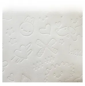 Detail view of white tote bag featuring embossed cartoon patterns and soft leather texture
