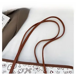 Close-up of durable brown leather shoulder straps on a graffiti canvas tote bag