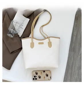 Detailed macro view of white embossed leather tote bag with brand logo and phone for scale