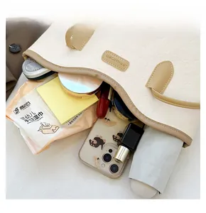 Spacious interior of cream tote bag showing capacity for phone, umbrella and cosmetics