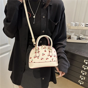 White cherry print shell shaped handbag with red trim and detachable shoulder strap