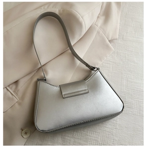 Detailed close-up of a silver metallic underarm bag placed on a beige blazer