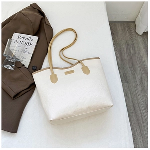 Detail of white tote bag with heart embossing, brown handles, and elegant brand logo plate