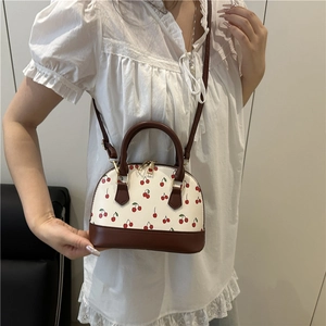 Chic shell-shaped cherry print handbag with brown handles and a long shoulder strap