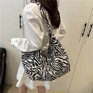 Large zebra print tote bag shown on model featuring casual black and white canvas design