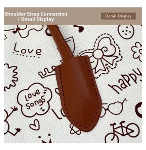 Close-up of doodle canvas tote with reinforced brown leather strap stitching